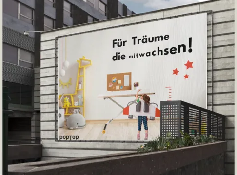 Das Plakat großflächig an einer Hauswand in der Stadt.